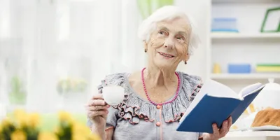 Old lady holding a cup and a blue-covered book