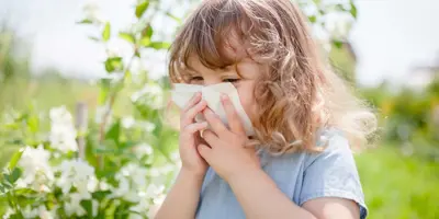 Little girl blowing her nose to relieve pollen allergy