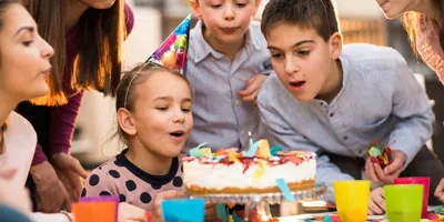 Children standing around a cake on a kids birthday party