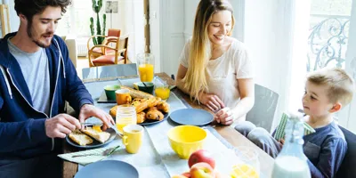 A family of three sitting around a table having breakfast in the morning