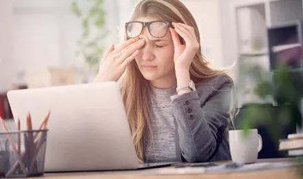 Young woman suffering from eye strain while working on a laptop which is one of the causes of watery eyes