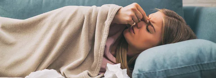 Woman lying in a blue sofa feeling sinus pain