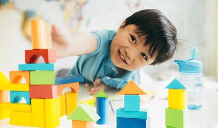 A young boy playing with colourful wooden toys